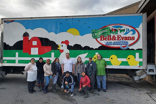 Volunteers pose in front of a delivery truck.